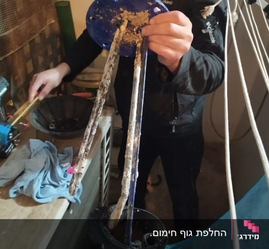 אדם מחזיק חלקי דוד שמש עם אבנית